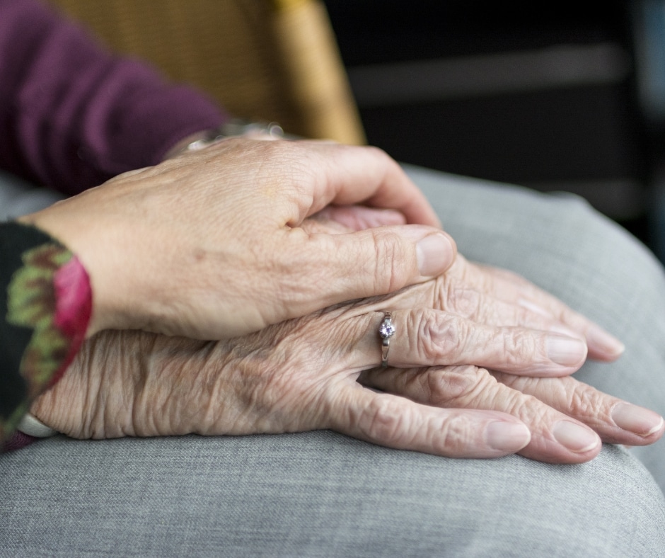 MN budget and senior care implications is depicted by young hand resting on senior's hand