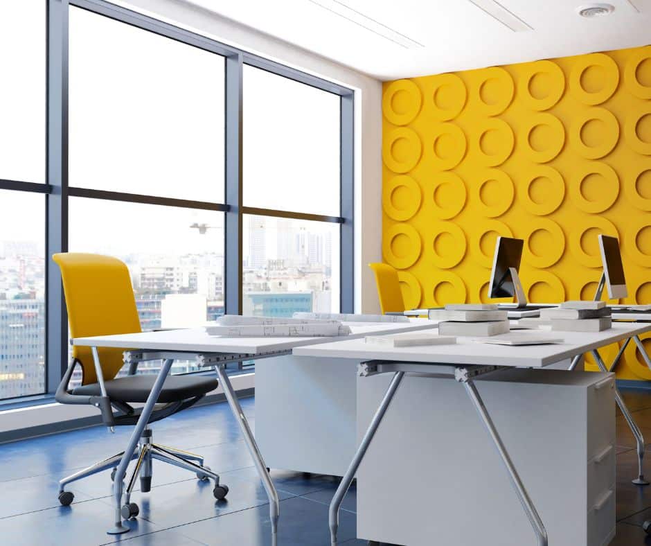 White neutral office with a bold yellow wall and chair demonstrates trending building design in 2025.