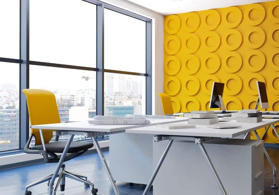 White neutral office with a bold yellow wall and chair demonstrates trending building design in 2025.